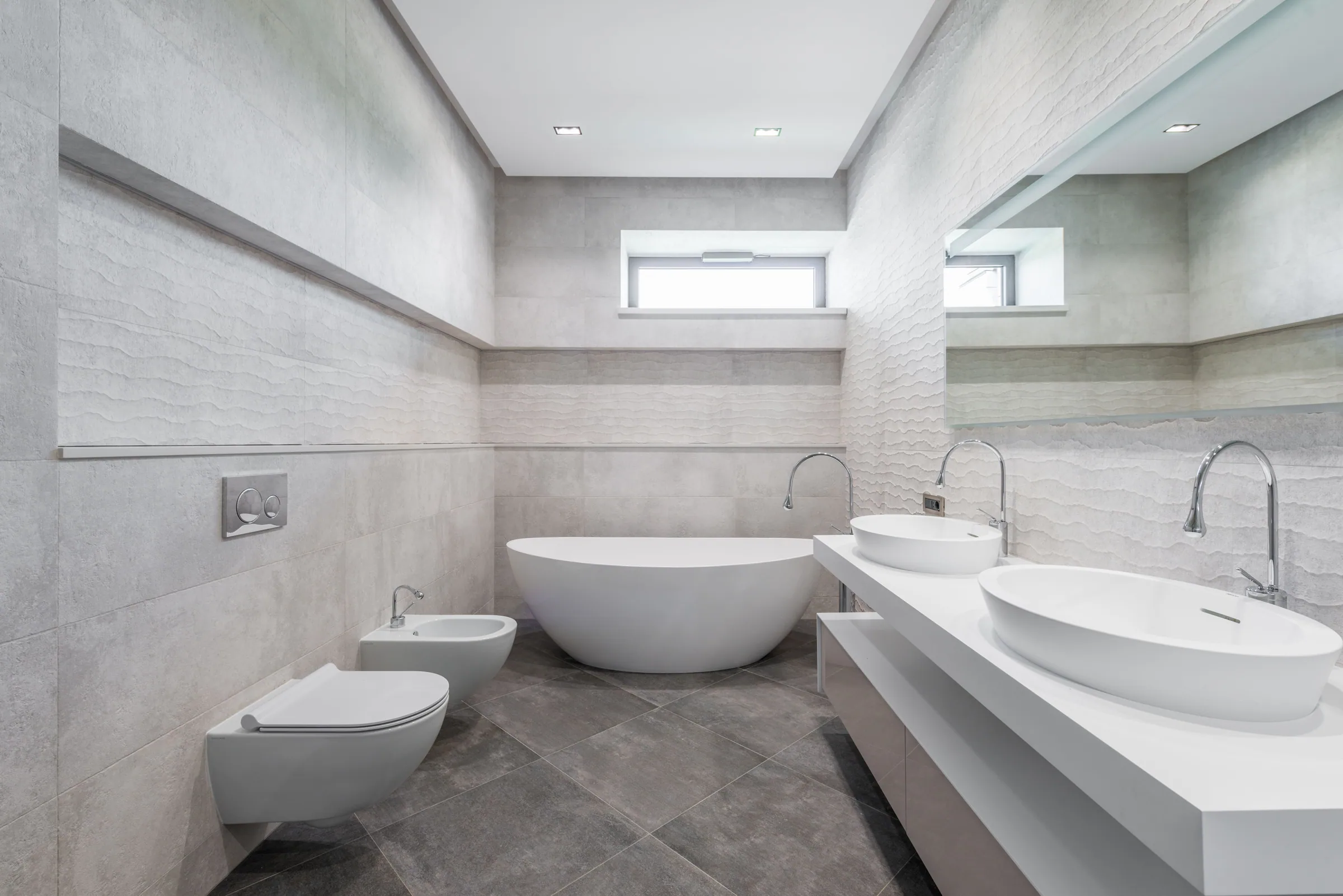 Minimalist light-gray bathroom with a freestanding bathtub and double sinks