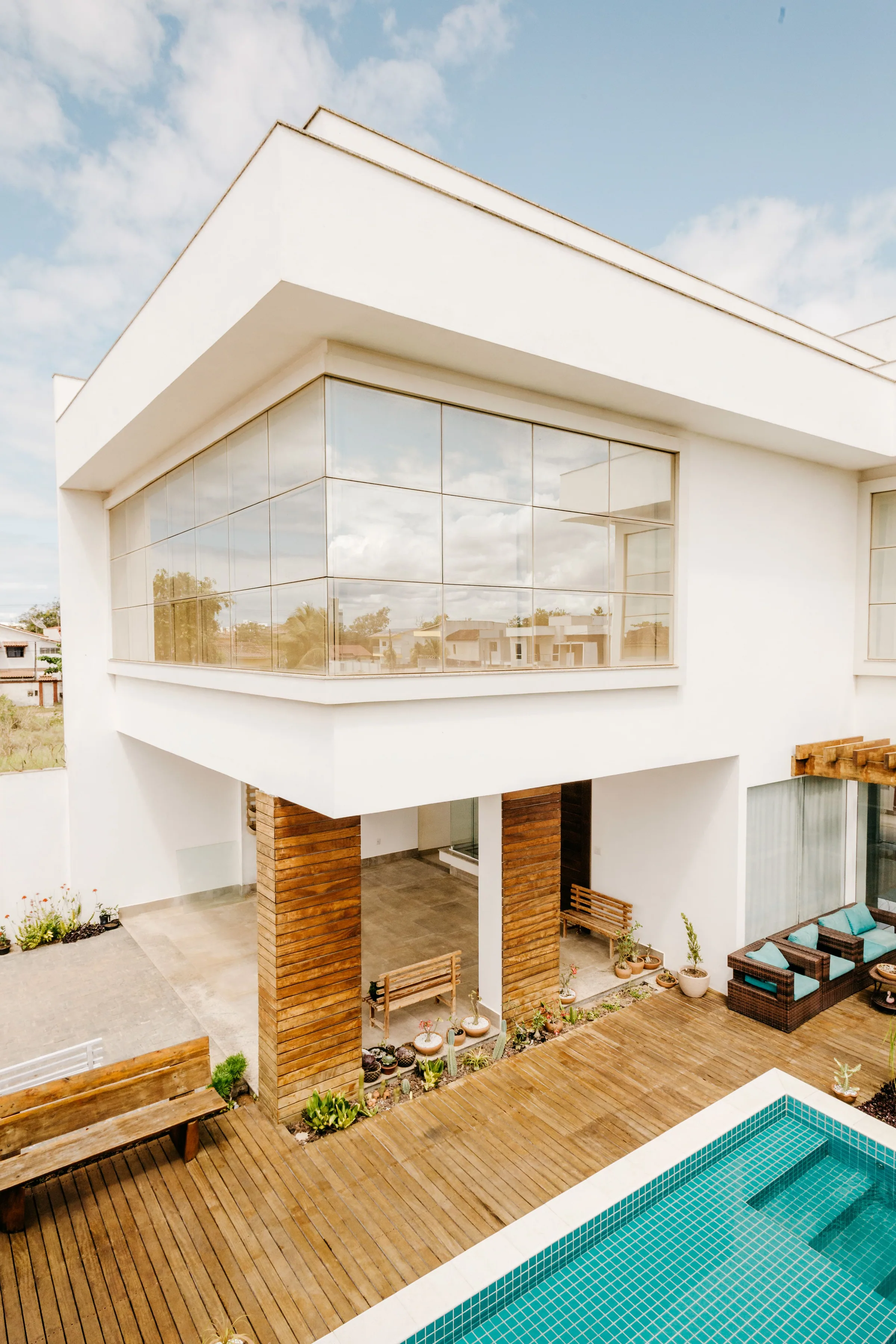 Modern white residence with a glass facade, timber deck and swimming pool